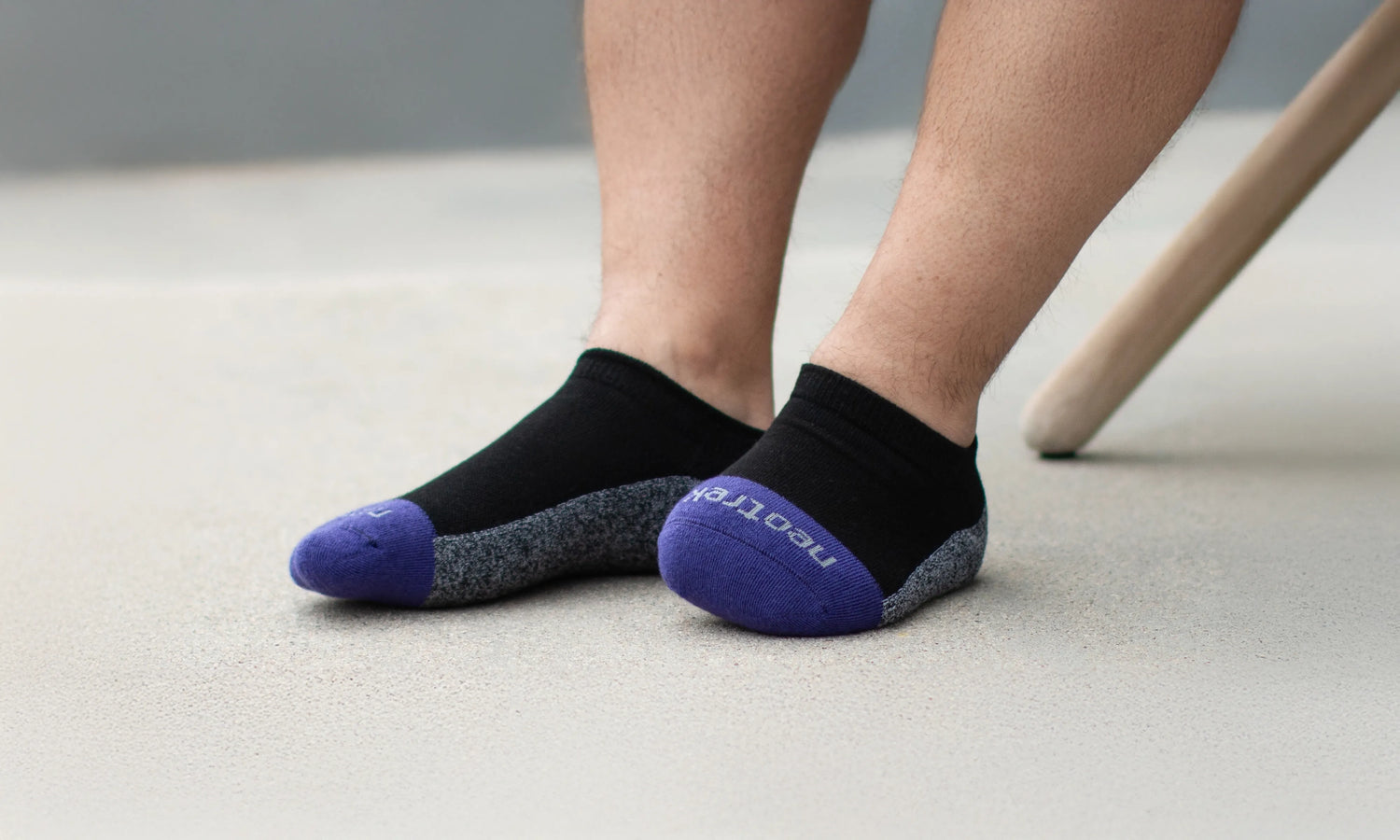 Person wearing black partial-foot amputee socks with purple toes and cuffs on a light background